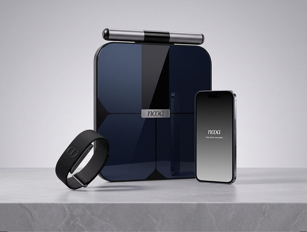 NOOA Smart Scale, Smart Band and the NOOA app on a phone, side by side on a stone surface