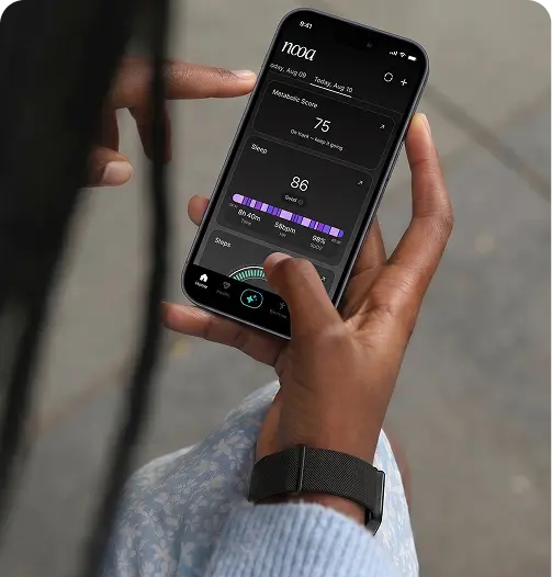 A hand holding a phone showing the NOOA app dashboard